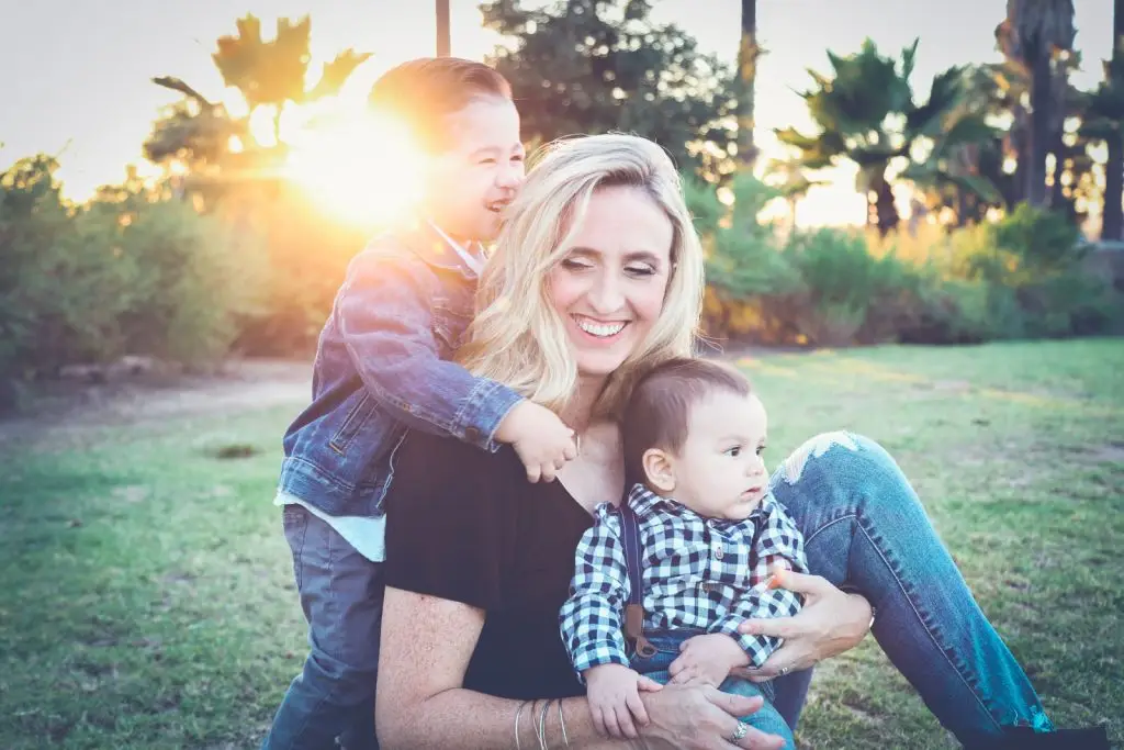 woman smiling while playing with two kids